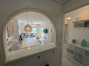 Eine moderne Küche mit Kochinsel, ein Essbereich mit Aussicht und ein Flur mit einem dekorativen Schrank.