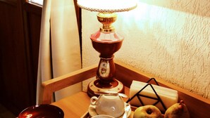 Una mesa de madera con una lámpara, tazas, un cuenco y frutas.