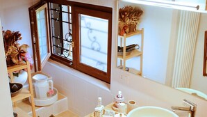 Un baño con un lavamanos grande, una ventana con vistas a la nieve, un espejo y un estante con artículos de aseo.