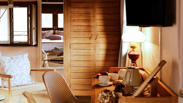 Una habitación acogedora con una cama de madera, una mesa de comedor con sillas, un televisor montado en la pared y una ventana con vistas.