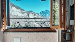 Un balcón con vista a la montaña, una silla de mimbre y un cabecero de madera.