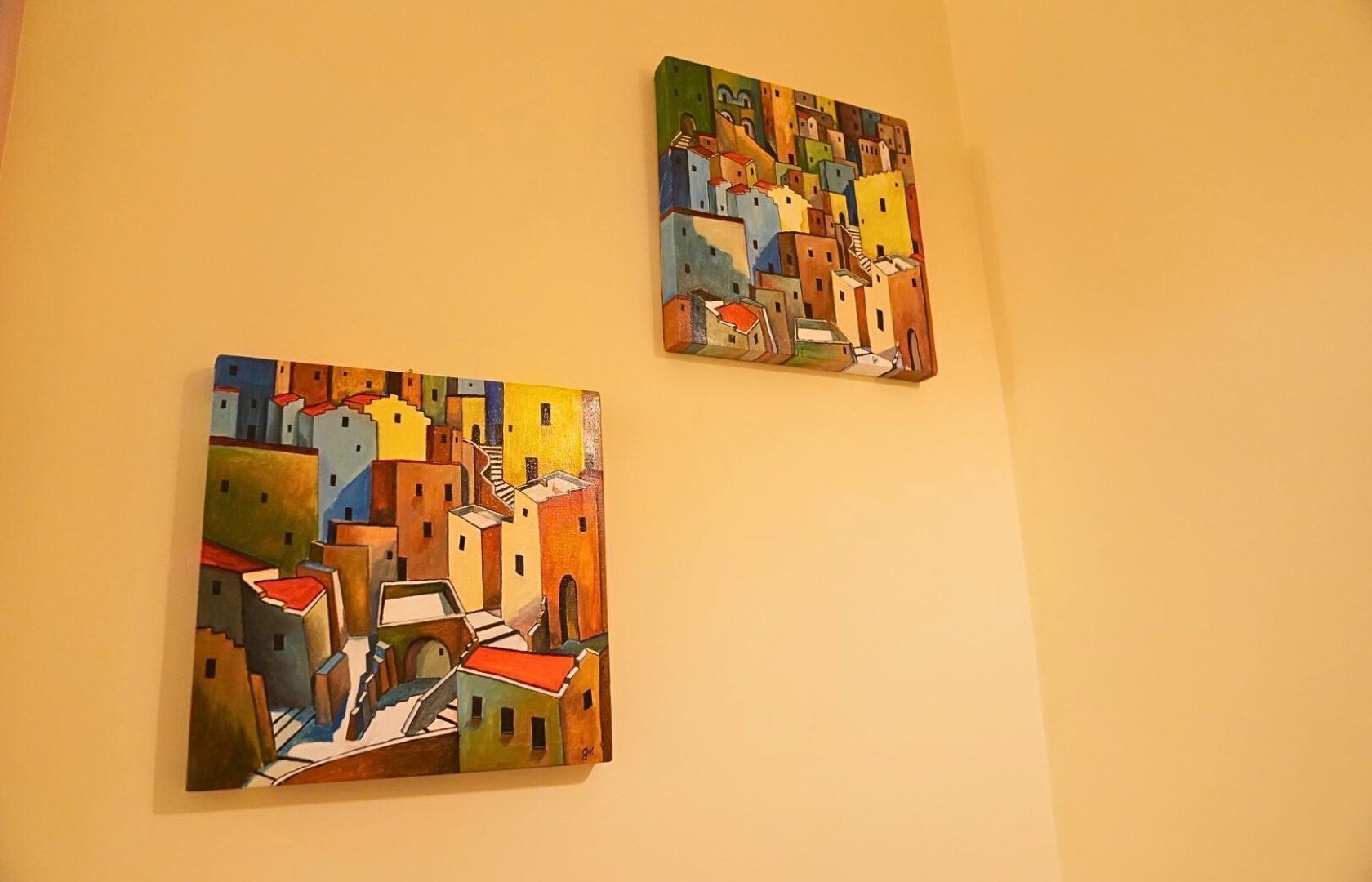 Dos cuadros de edificios coloridos sobre una pared lisa.