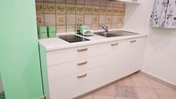 Una cocina con gabinetes blancos, un lavamanos doble y contenedores verdes para guardar, etiquetados 'SUGAR' y 'COFFEE'.