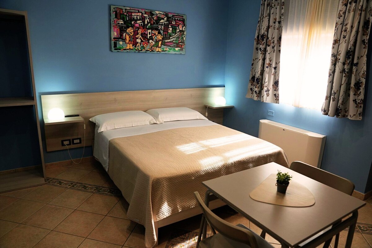 A bedroom with a bed, bedside tables, a desk, and a chair.