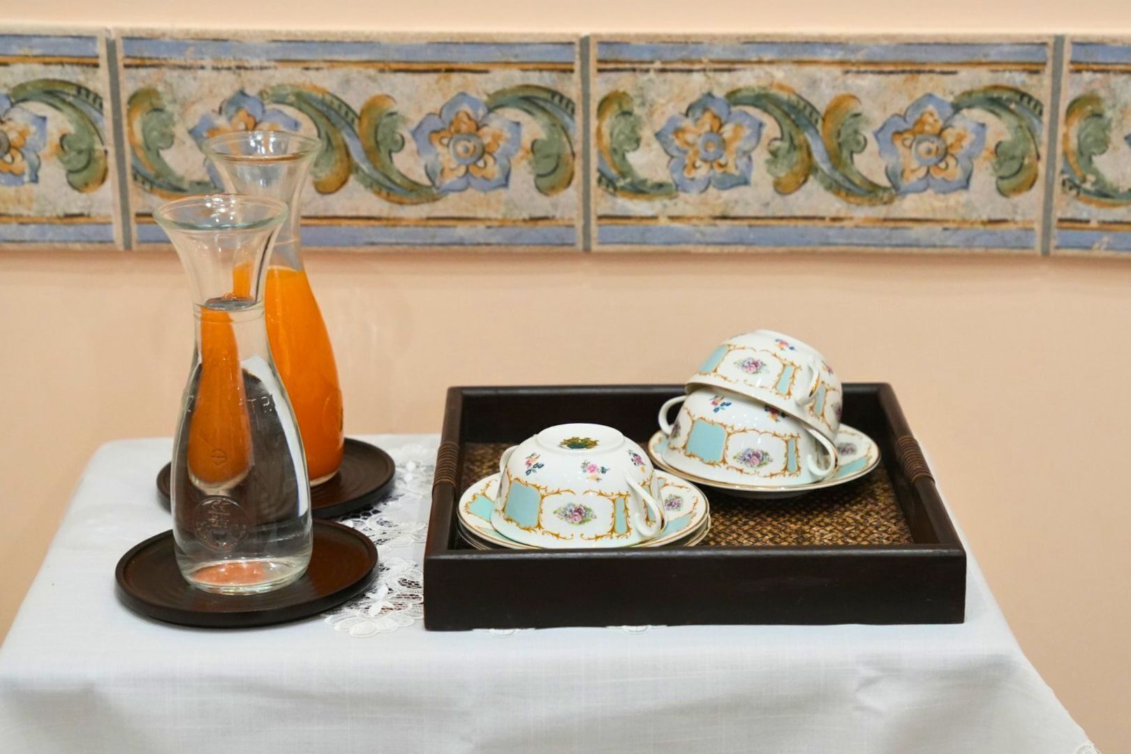 Una mesa con un jarrón de cristal, una botella y una bandeja con tazas de té.