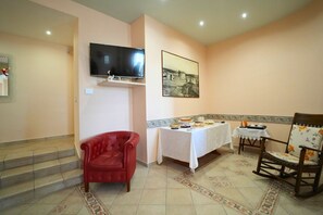 Una habitación con televisión, una mesa de comedor con comida, una silla roja y un piso con diseño.