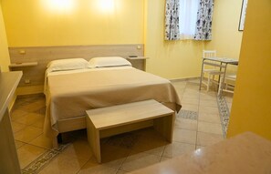 A hotel room with a bed, bedside tables, a bench, a small table, and a chair. - Villa Vittoria (Matera)