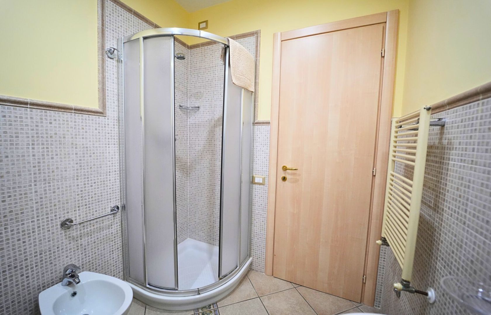 Une salle de bain avec une douche, un lavabo et une porte en bois.