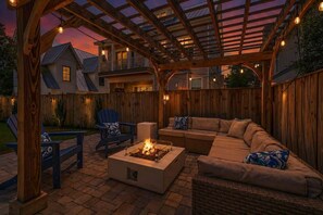 A covered outdoor patio with a fire pit, seating area, and wooden pergola. - Ocean Pearl by Stay on 30a (Inlet Beach)