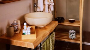 Une salle de bain avec un meuble-lavabo en bois, un grand lavabo blanc, un miroir, un porte-serviettes et un espace douche.