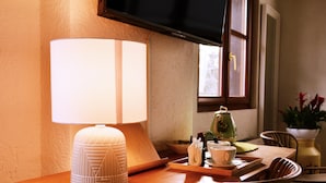 Une table en bois, sur laquelle se trouvent une lampe blanche, une théière verte et une tasse blanche, le tout posé sur un plateau.