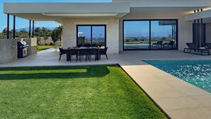 Een modern huis met zwembad, eethoek en barbecue.
