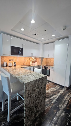 A modern kitchen with white cabinetry, a granite island, and a marble backsplash. - Upgraded, sparkling clean 1 BR apt. w/balcony. Full Marina view. 5 min to beach (Dubai)