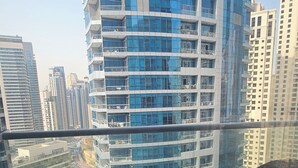 Un balcón con mobiliario de mimbre y vistas a edificios altos.