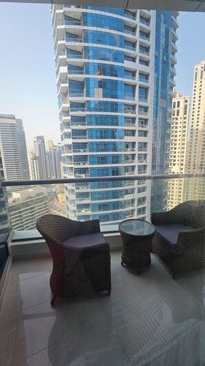 A balcony with wicker furniture and a view of high-rise buildings. - Upgraded, sparkling clean 1 BR apt. w/balcony. Full Marina view. 5 min to beach (Dubai)