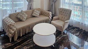 Una sala de estar moderna con un sofá seccional, una mesa de centro redonda y un sillón tapizado.