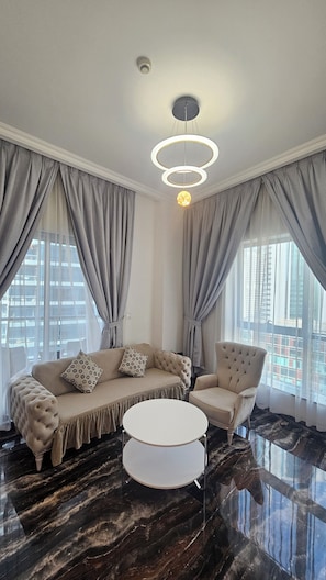 A modern living room with a sectional sofa, a round coffee table, and a tufted armchair. - Upgraded, sparkling clean 1 BR apt. w/balcony. Full Marina view. 5 min to beach (Dubai)