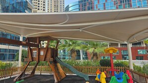 Un parque infantil con tobogán, columpios y una estructura para escalar.