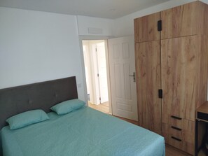 A bedroom with a bed, a wardrobe, and a door leading to another room.