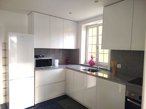 A kitchen with white cabinets, a microwave, a sink, and a window. - 4 - The Floor House 4 Bedrooms Center (Guimarães)