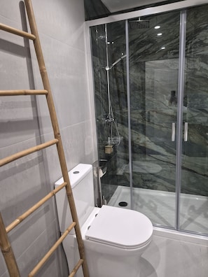 A modern bathroom with a glass shower enclosure, a white toilet, and a wooden ladder. - 4 - The Floor House 4 Bedrooms Center (Guimarães)