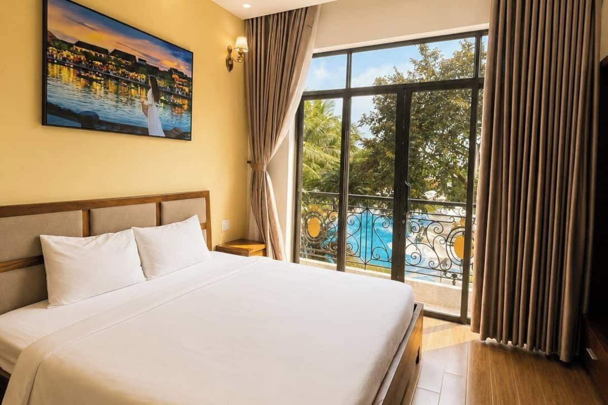 A hotel room with a large bed, a painting on the wall, a window with curtains, and a view of a pool.