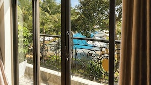 Una habitación con grandes puertas correderas de vidrio que dan a un balcón con piscina y vegetación.