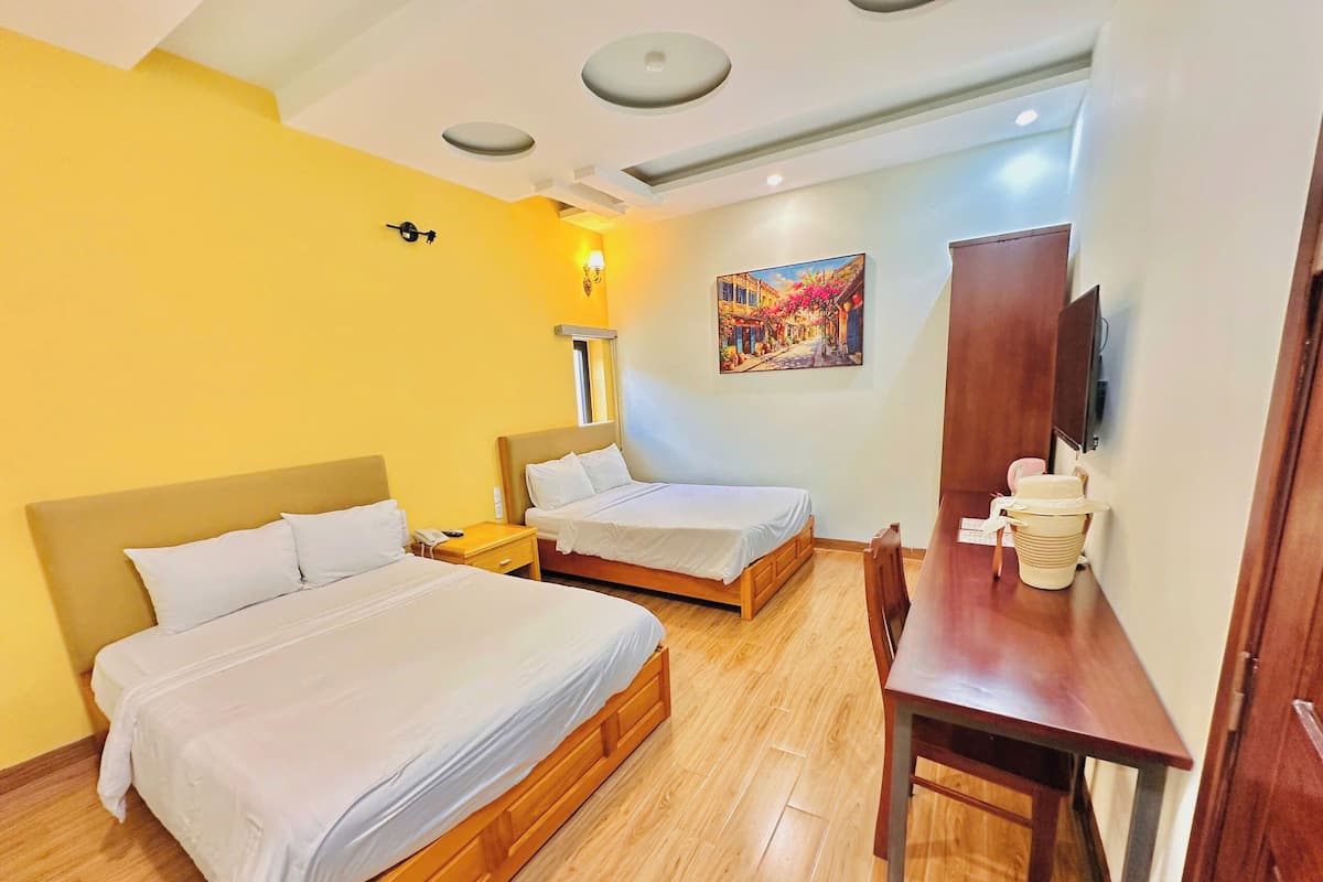 A hotel room with two beds, a desk, a chair, a lamp, a painting, and a television.