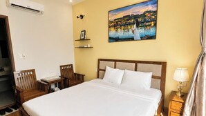 Habitación de hotel con una cama grande, un escritorio, una silla, una mesita de noche, una lámpara y un cuadro en la pared.