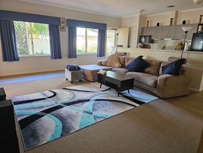 A living room with a sofa, ottoman, coffee table, and a patterned rug.