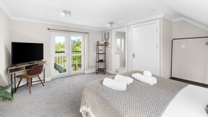 Un dormitorio con cama, televisor, escritorio y silla.