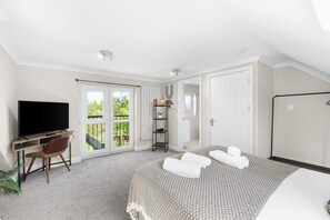 A bedroom with a bed, a TV, a desk, and a chair. - Stylish 5 Bed Surrey Home with Garden (Leatherhead)