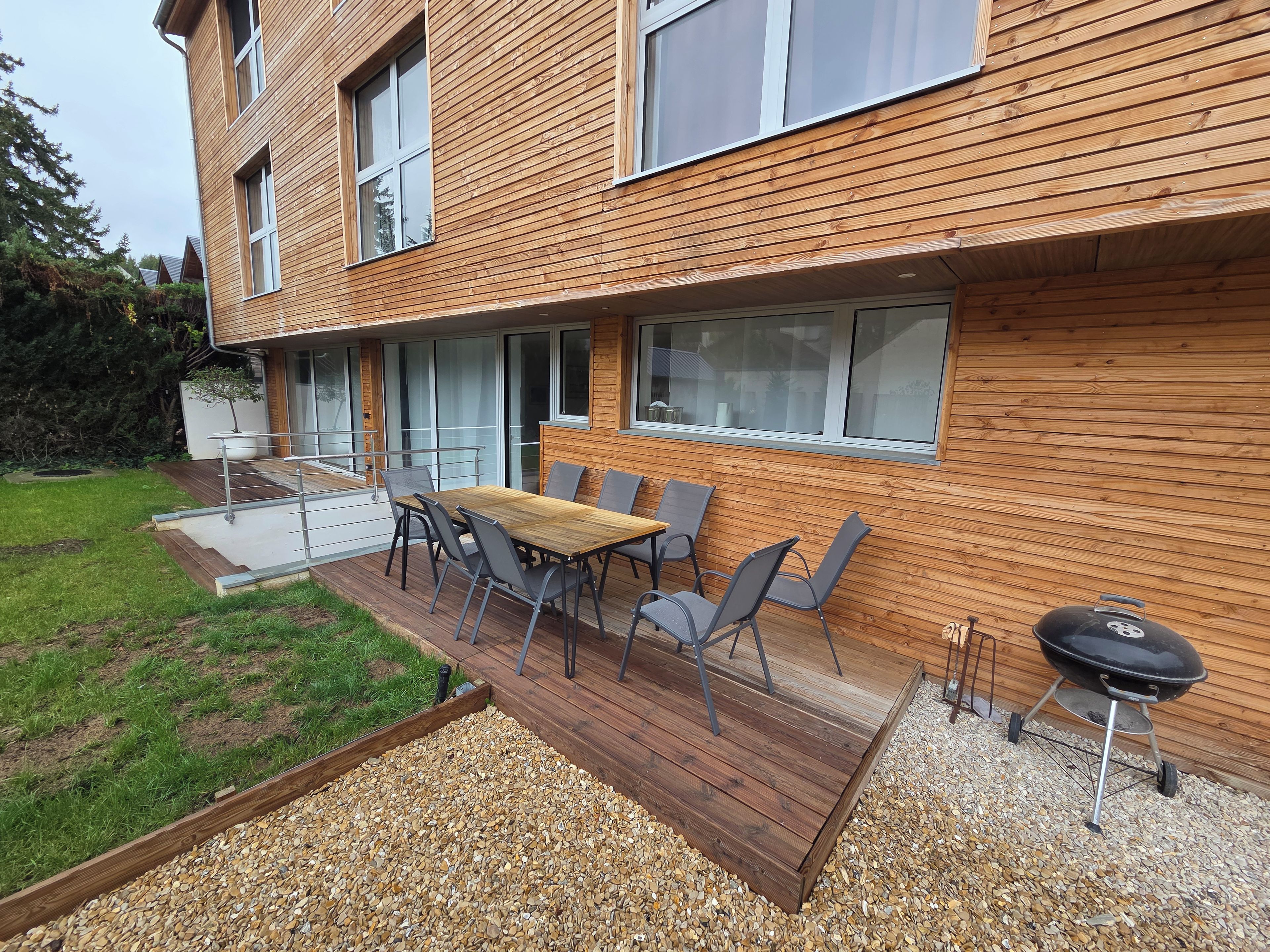 Ein modernes Haus mit einer Terrasse, Sitzgelegenheiten im Freien und einem Grill.