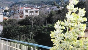 Ein Wohngebiet mit Häusern, einem Berg im Hintergrund und einem Balkon mit Geländer.