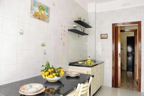 A kitchen with white tiled walls, black countertops, and a wooden door. - VicoStay by Casa Stella: Relaxation with a View in the Heart of the Sorrento Coast (Vico Equense)
