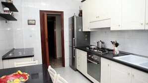 Eine Küche mit weißen Schränken, einer schwarzen Arbeitsplatte, einem Kühlschrank, einem Herd und einem Spülbecken.