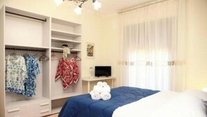 Ein Schlafzimmer mit einem Bett, einem Kleiderschrank, einem Fernseher und einem Fenster mit Vorhängen.