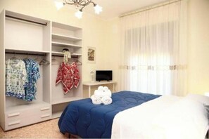 A bedroom with a bed, a wardrobe, a television, and a window with curtains. - VicoStay by Casa Stella: Relaxation with a View in the Heart of the Sorrento Coast (Vico Equense)