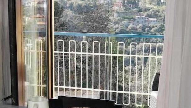 Ein Balkon mit Metallgeländer, einem Tisch mit weißer Tischdecke und Blick auf eine Berglandschaft.