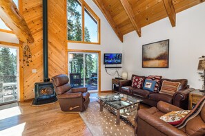 A spacious living room with a fireplace, leather furniture, large windows, and a TV. - Timberline Lodge_AC, Sauna, Shuffleboard (Truckee)