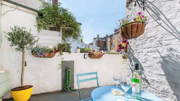 Pequeña zona de estar al aire libre con una mesa redonda, sillas y una botella de agua.