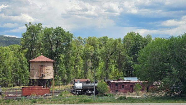A rustic train station with a wooden signal tower, a steam locomotive, and a caboose.