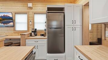 Una cocina moderna con armarios blancos, un refrigerador de acero inoxidable y encimeras de madera.