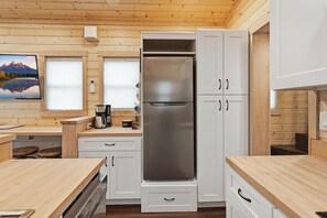A modern kitchen with white cabinets, a stainless steel refrigerator, and wooden countertops.