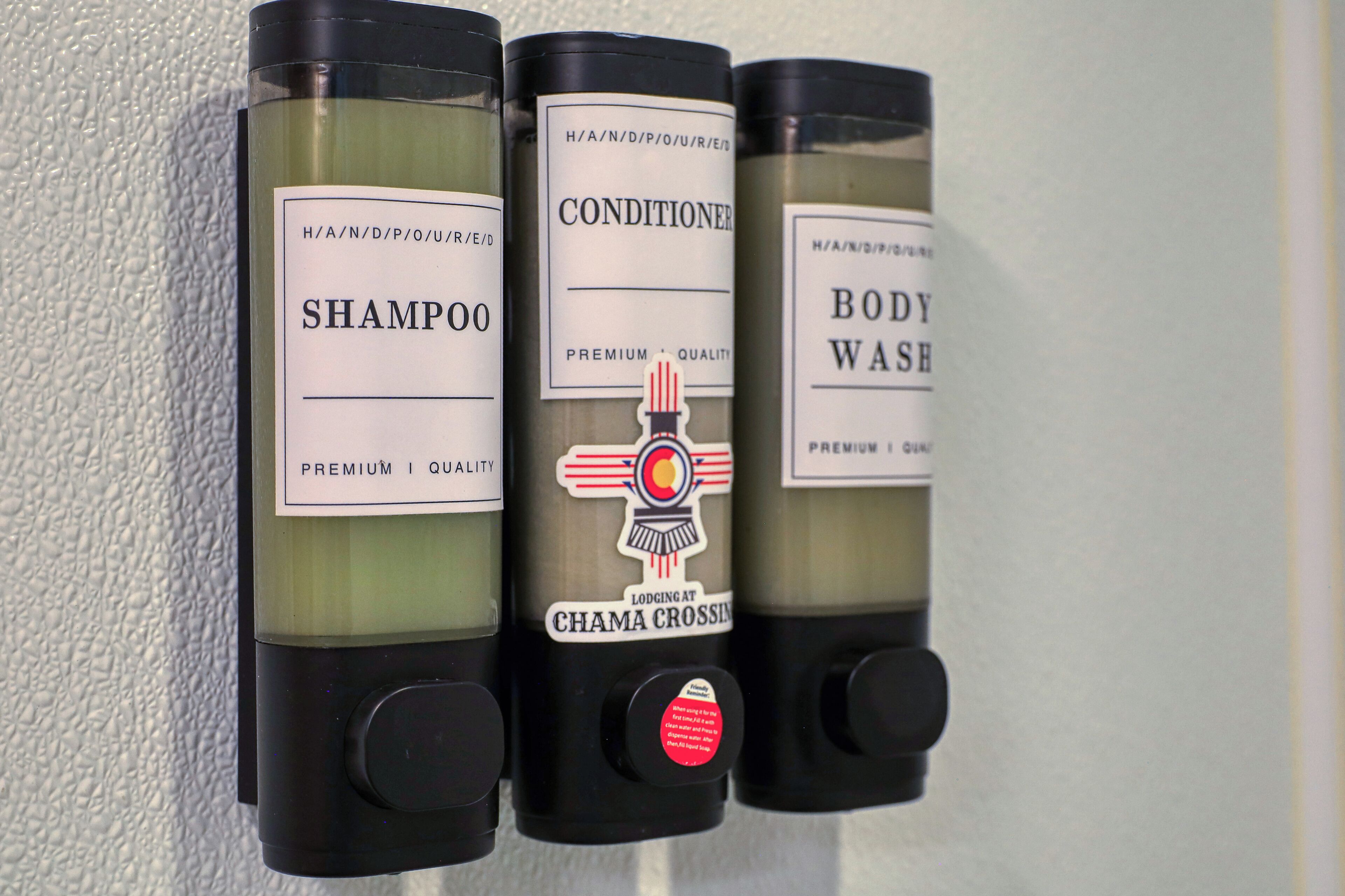 Three bottles of shampoo, conditioner, and body wash with labels and pumps.