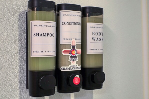 Three bottles of shampoo, conditioner, and body wash with labels and pumps.