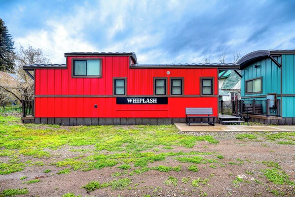 Un edificio rojo con el letrero 'WHIPLASH' y una banca afuera.