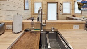 Una cocina moderna con paredes de madera, un lavamanos de acero inoxidable y una tabla de cortar de madera.