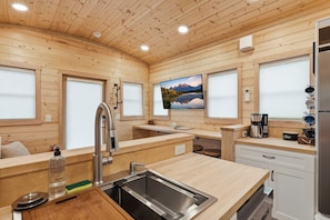 A modern kitchen with wooden walls, a stainless steel sink, and a coffee maker.