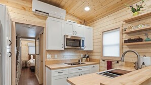 Una cocina moderna con armarios blancos, microondas de acero inoxidable y encimera de madera.